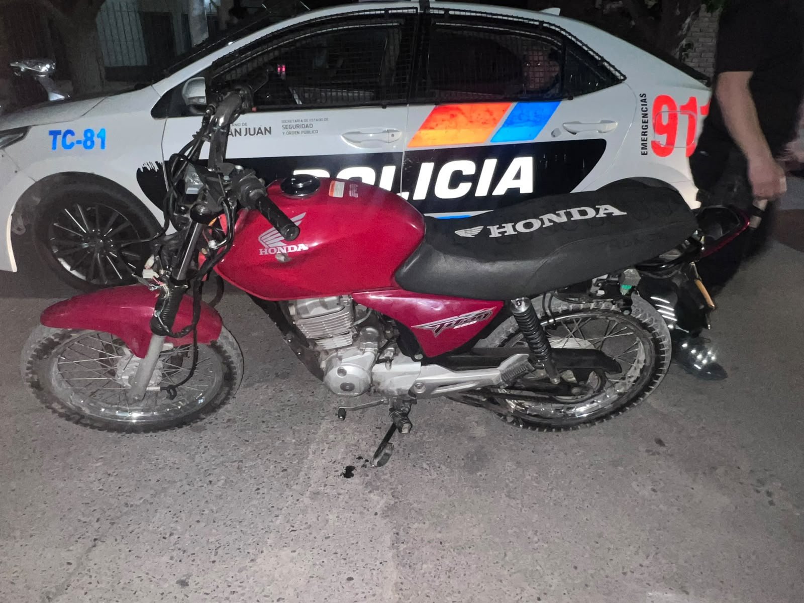 Honda CG Titan roja y mÃ³vil policial TC-81. CrÃ©dito PolicÃ­a de San Juan.