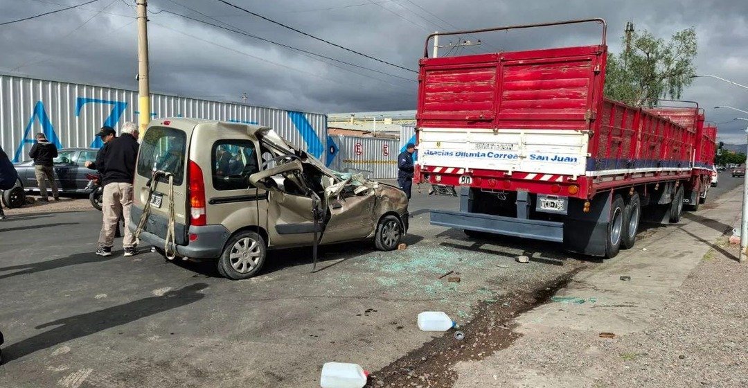 Una Renault Kangoo con el frente destruido junto a un camión rojo estacionado.