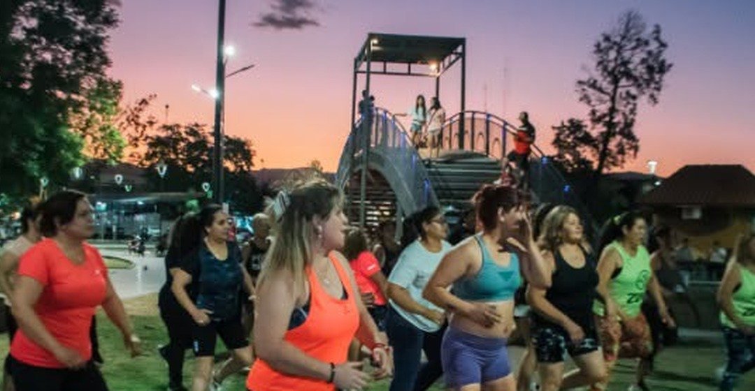 Mujeres hacen zumba en un parque de Rawson al atardecer.