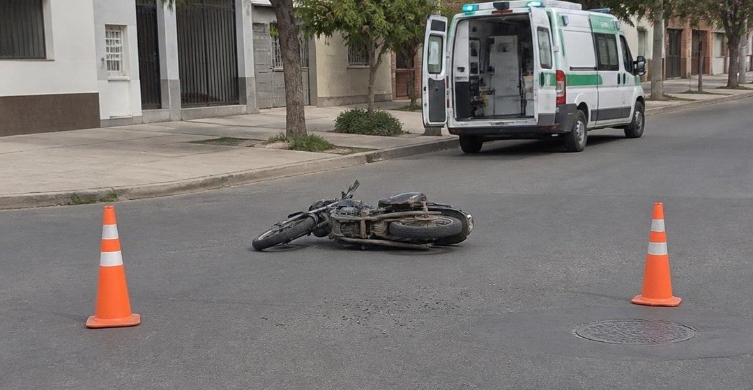 Moto caída en una intersección con conos y una ambulancia. Imagen ilustrativa.