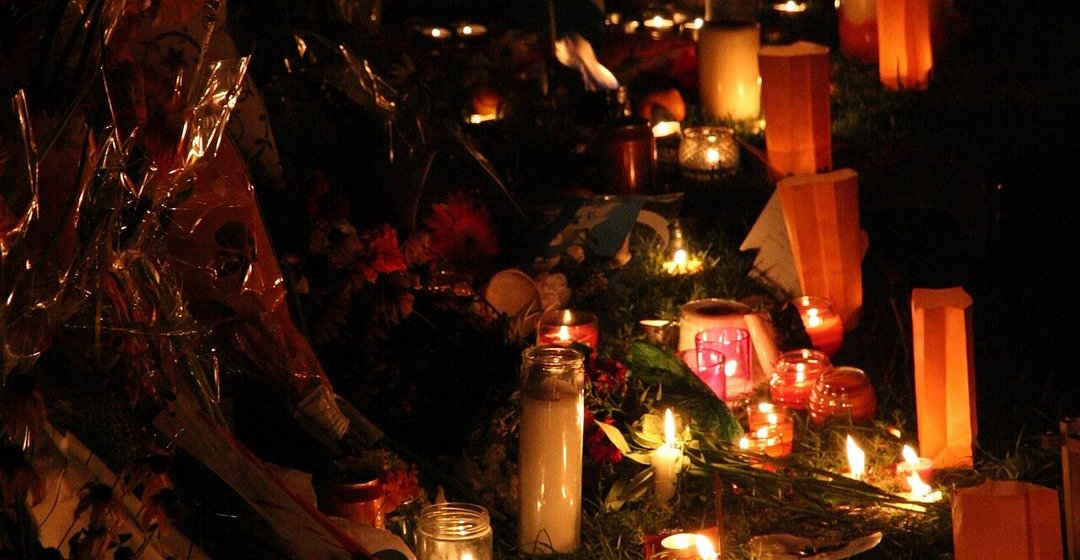 Velas encendidas y flores en un homenaje nocturno.