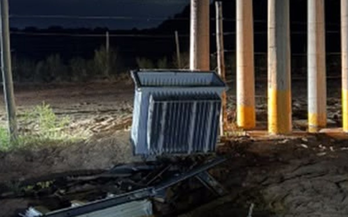 Transformador eléctrico de 200 KVA derribado junto a una estructura de postes, de noche.