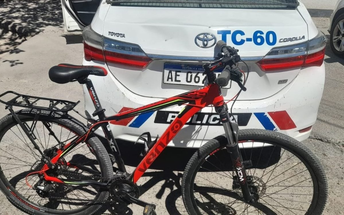 Bicicleta Venzo roja con detalles amarillos frente a un móvil policial TC-60.
