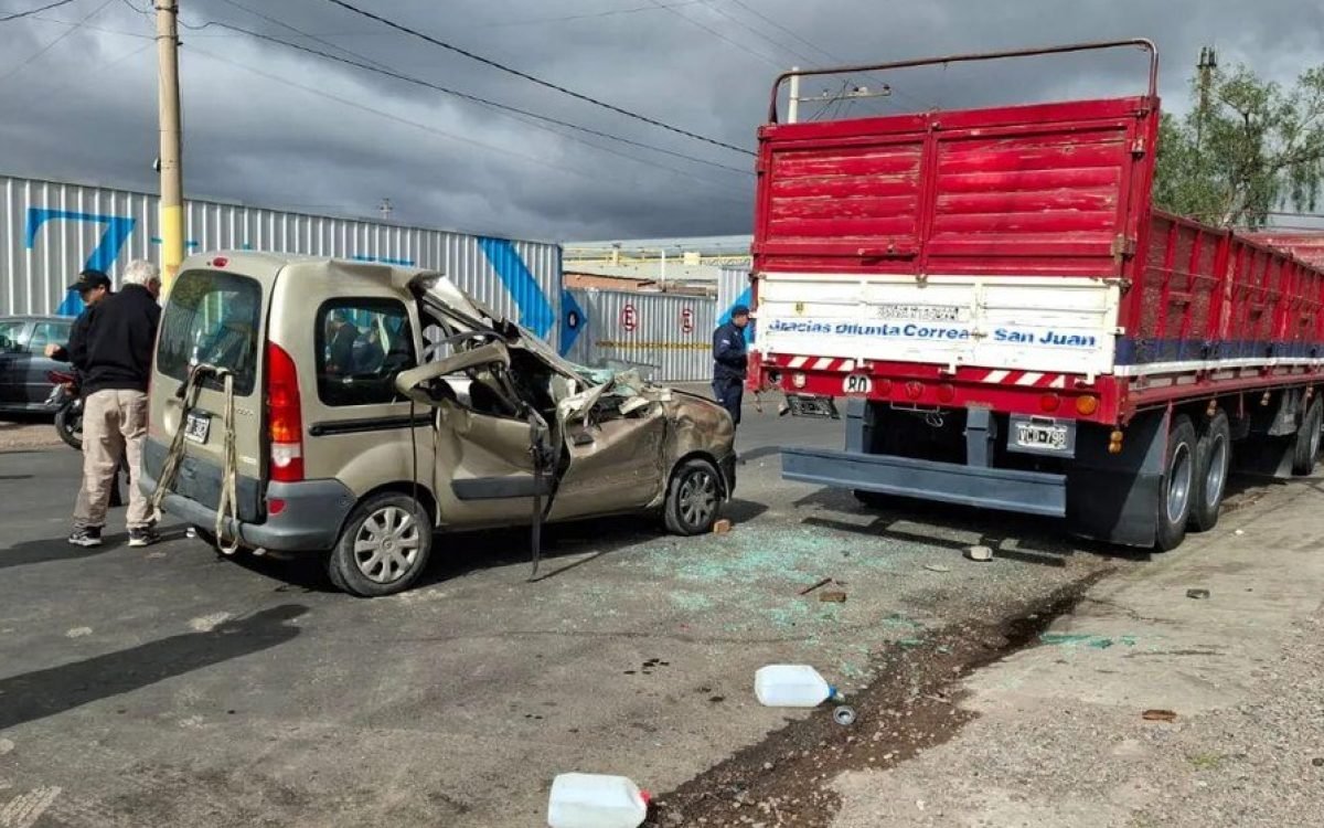 Una Renault Kangoo con el frente destruido junto a un camión rojo estacionado.