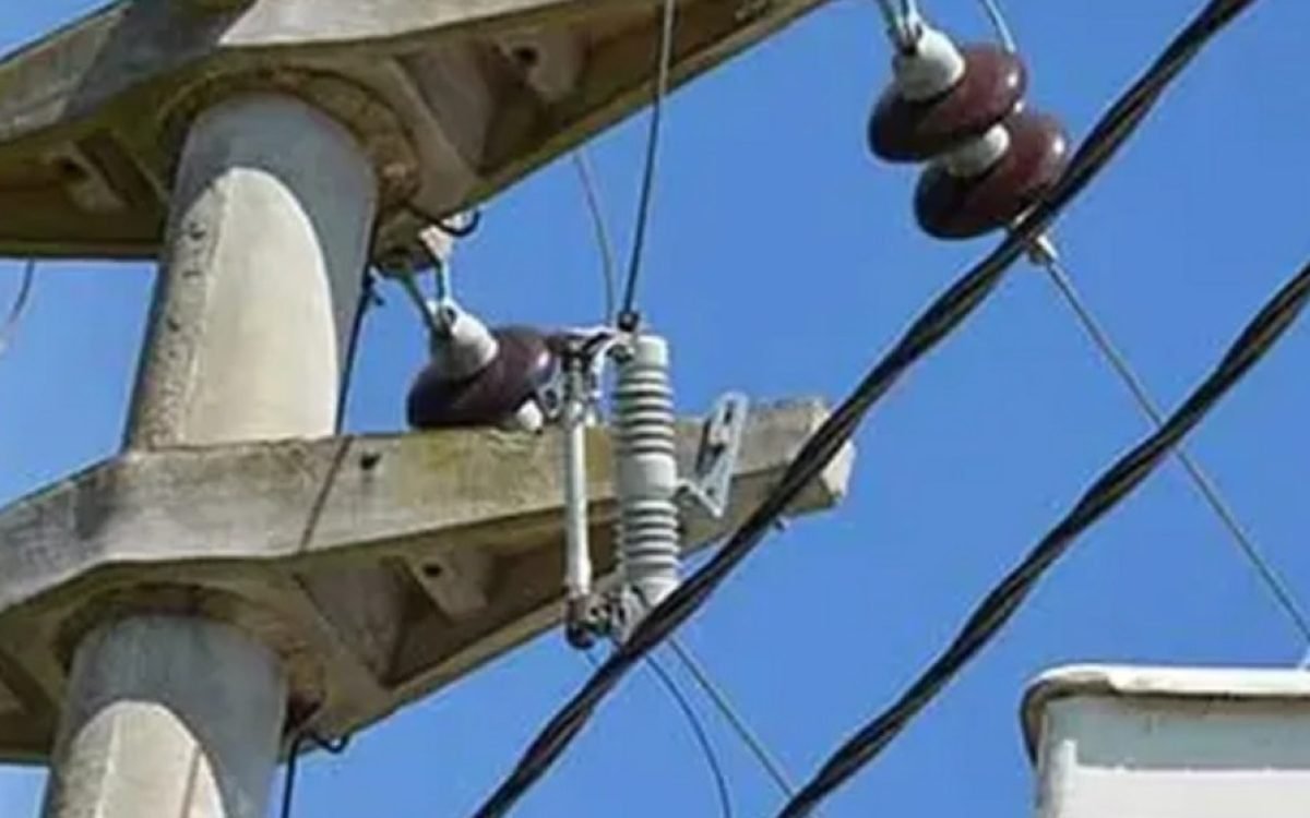 Un poste de hormigón con aisladores y cables de media tensión, contra el cielo azul.