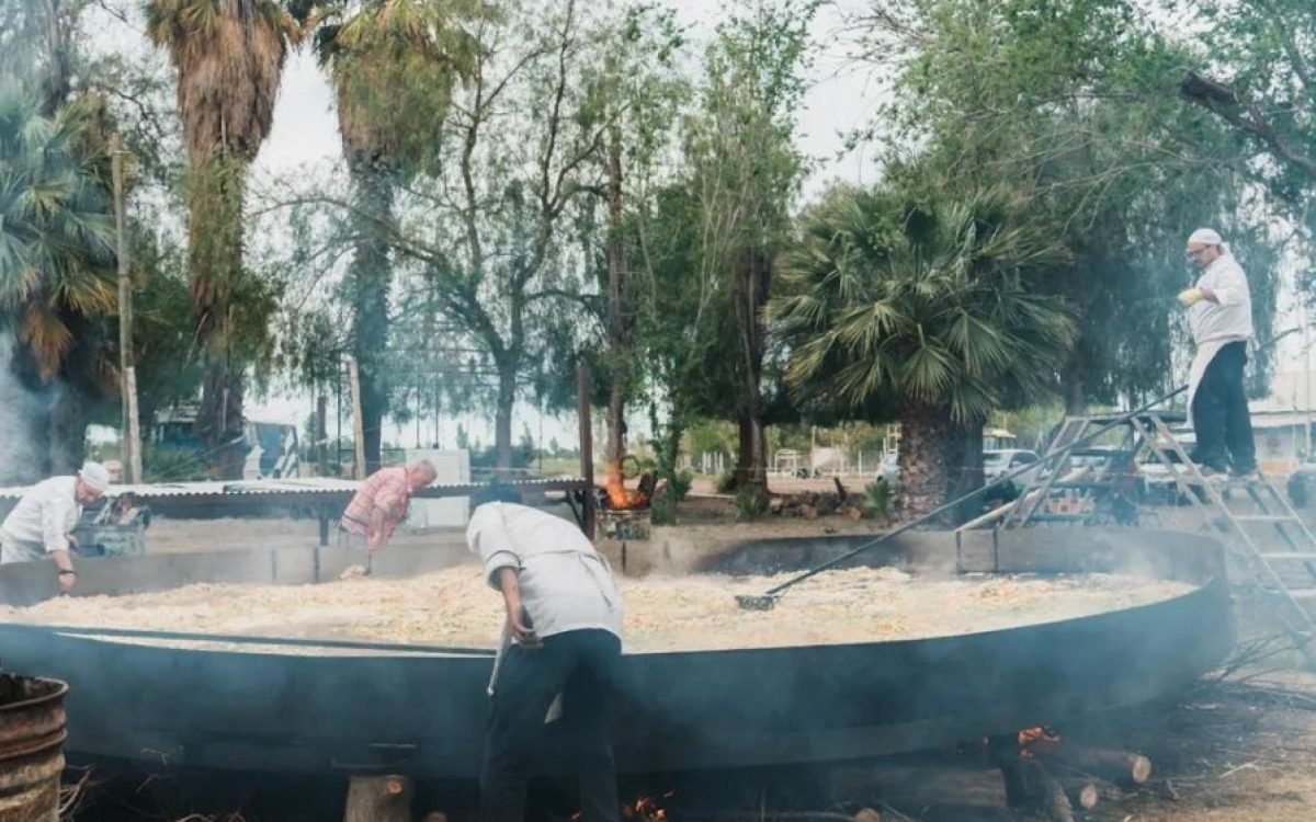 Cocineros preparando un risotto gigante a fuego de leña en el Predio Gaucho José Dolores.
