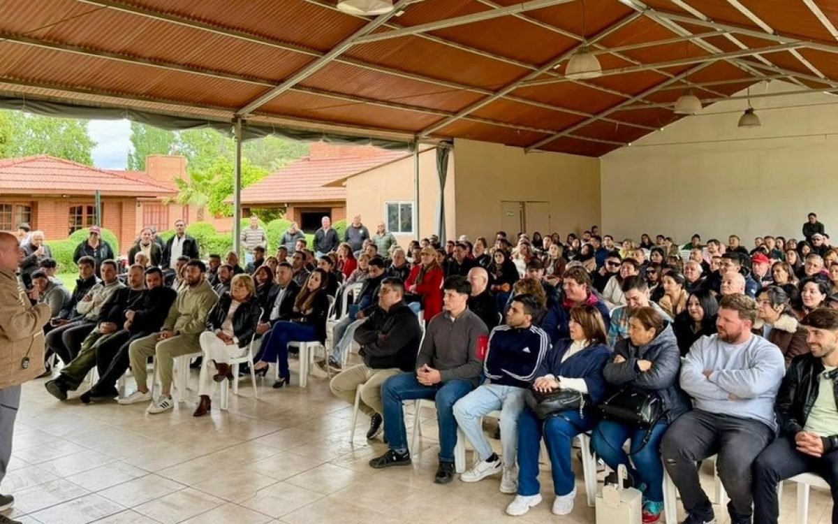 José Peluc habla de pie ante un salón colmado de militantes sentados en la Quinta Los Amigos, en Rawson.