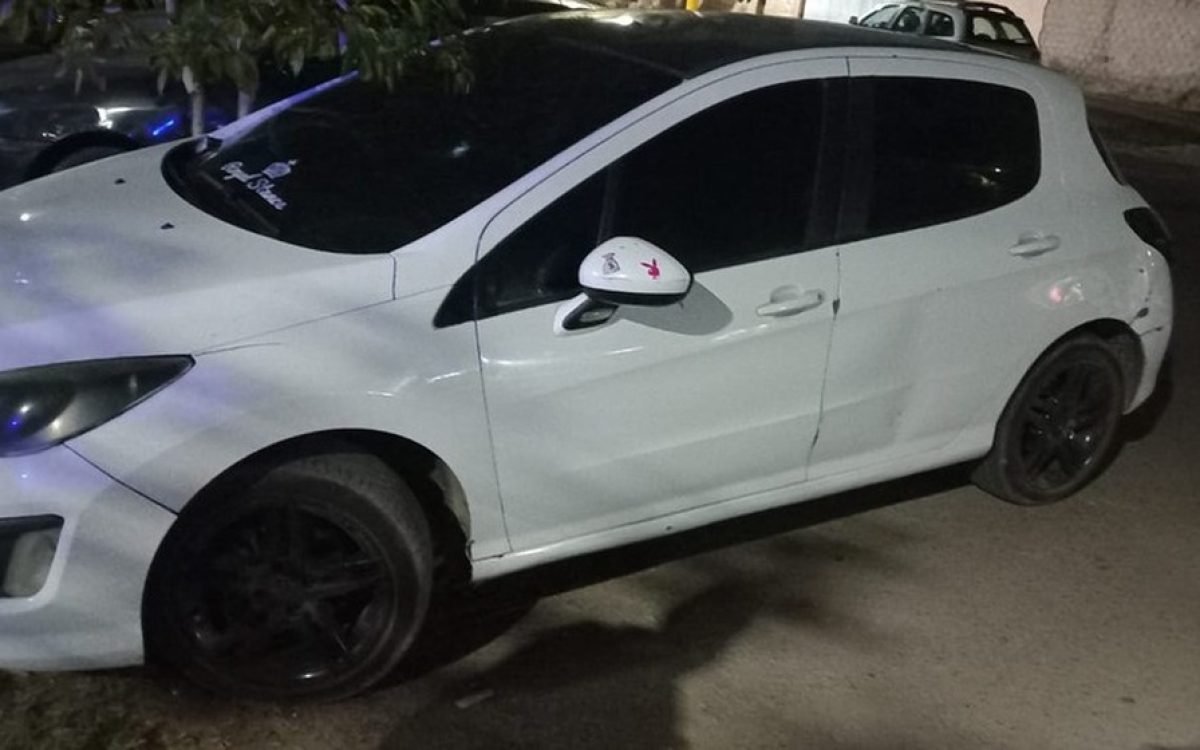 Un Peugeot 308 blanco estacionado de noche.