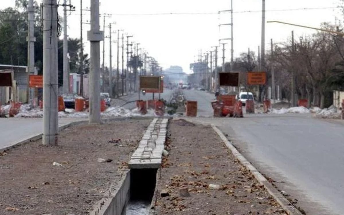 Calle con un corte de calzada, una zanja a cielo abierto y vallas naranjas, imagen de una obra vial.