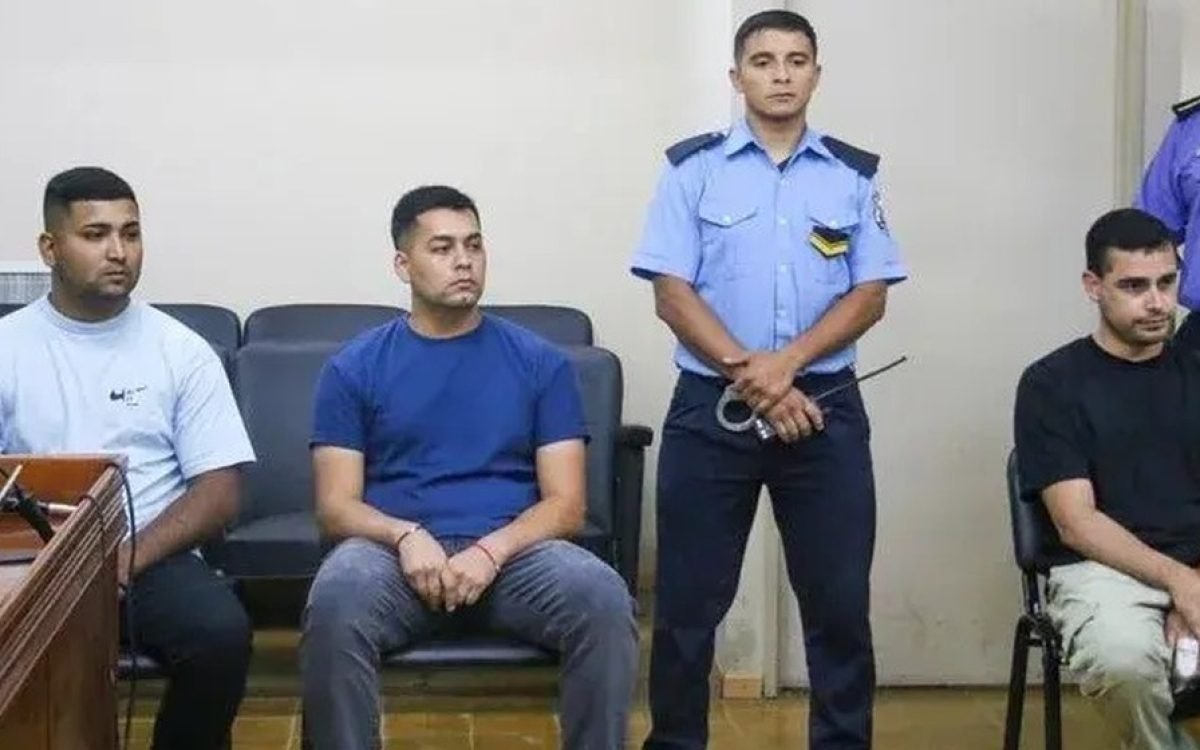 Tres hombres imputados sentados en una audiencia judicial, con personal policial.