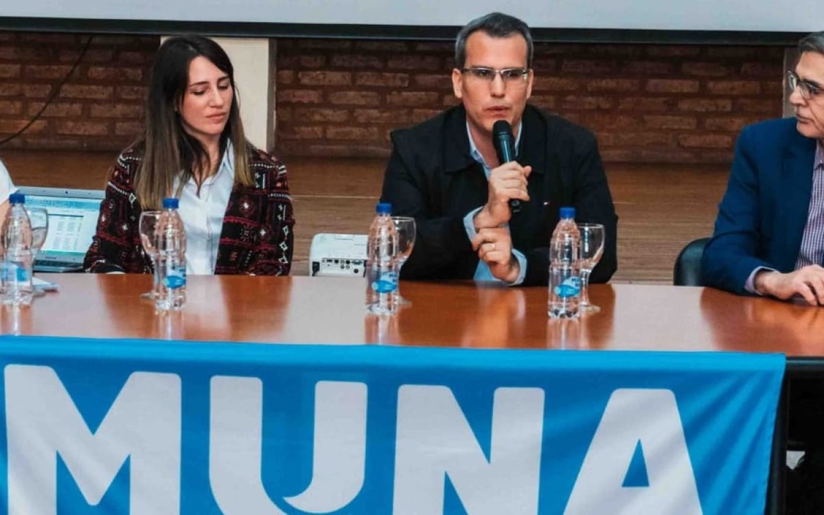 Mesa de autoridades en la presentación de MUNA en Rawson, con un banner celeste del programa.