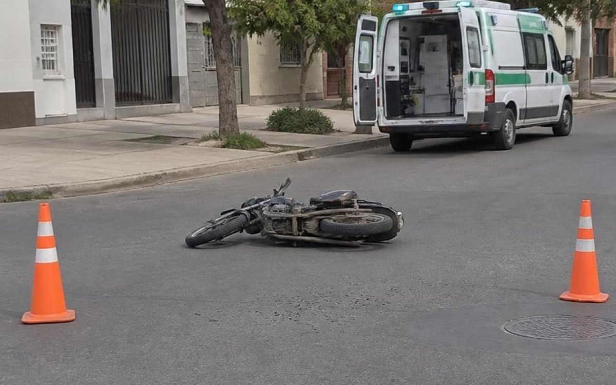 Moto caída en una intersección con conos y una ambulancia. Imagen ilustrativa.