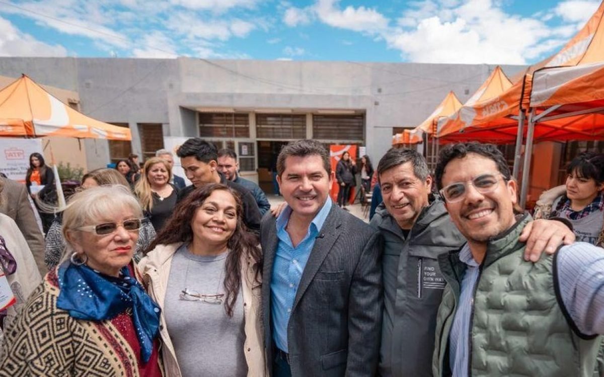 El gobernador Marcelo Orrego posa con vecinas y funcionarios frente a gazebos naranjas del operativo.