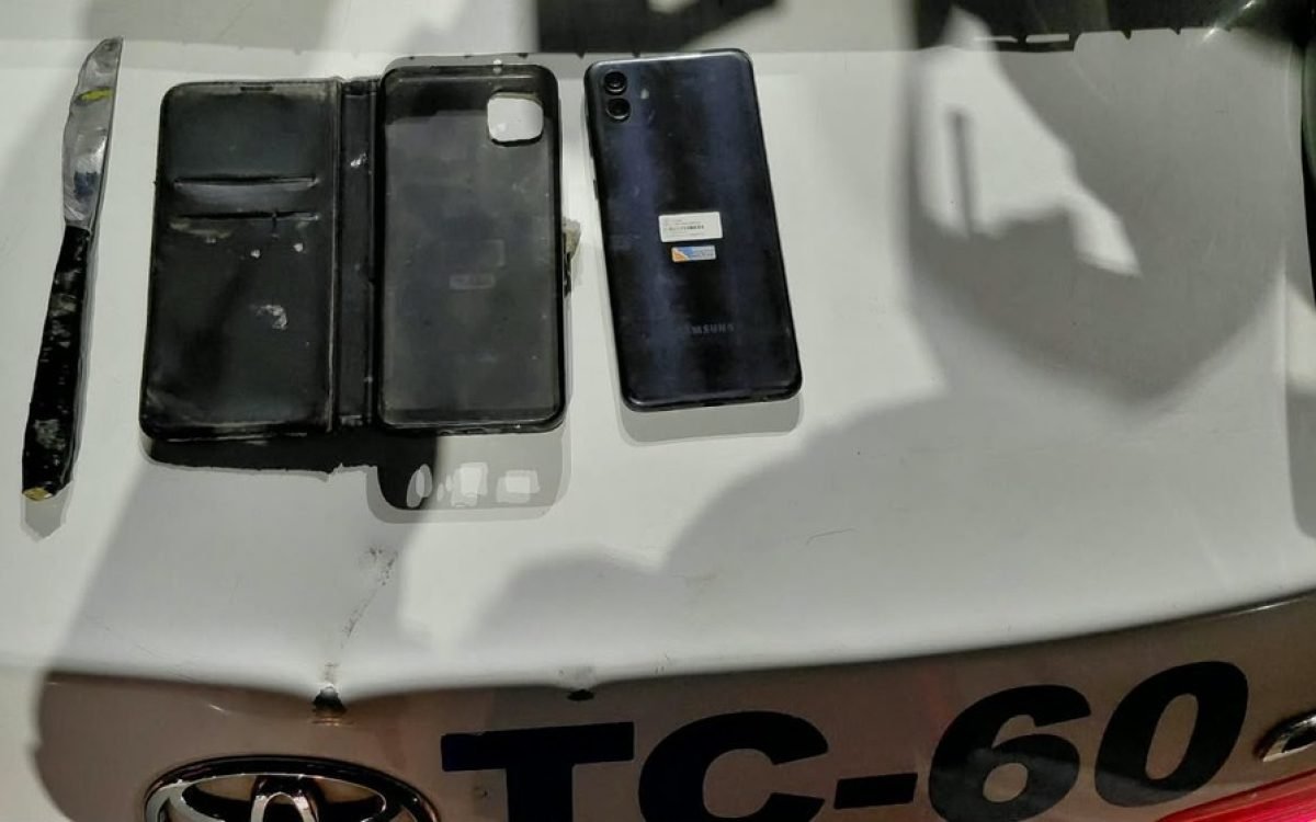 Un cuchillo, una funda tipo libro y un celular Samsung azul secuestrados, sobre el baúl de un patrullero.