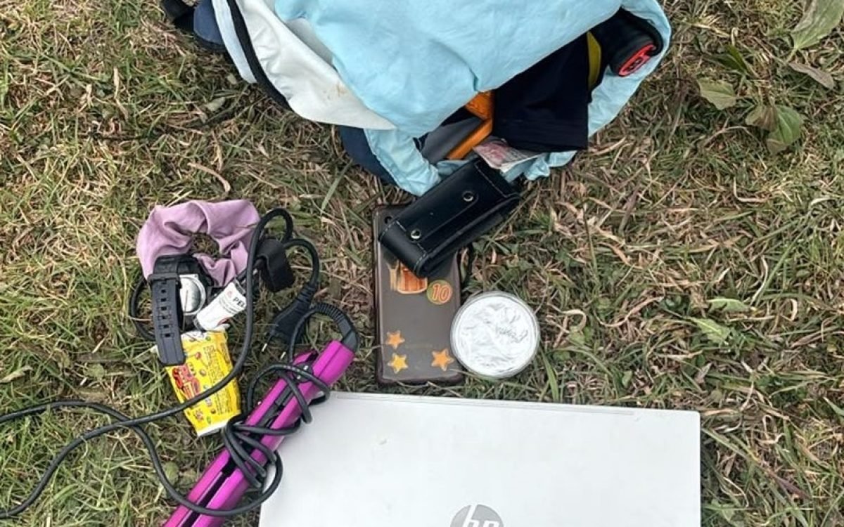 Mochila, notebook y otros objetos recuperados por la Policía sobre el pasto.