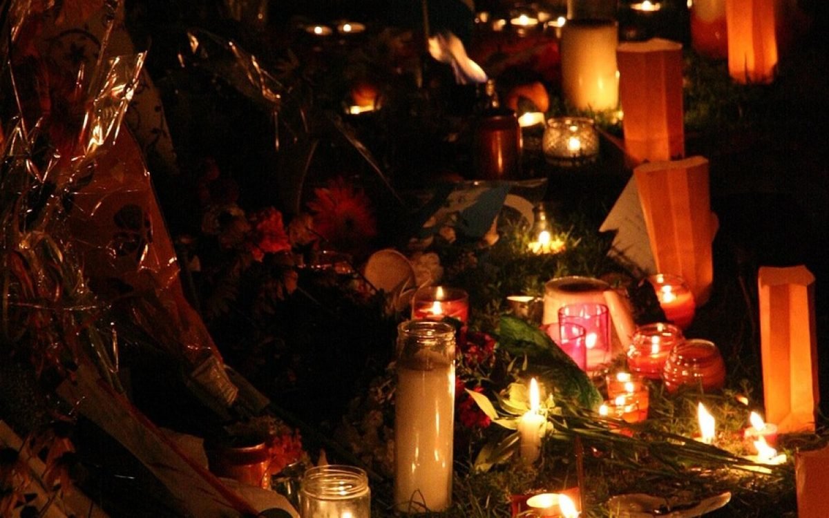 Velas encendidas y flores en un homenaje nocturno.
