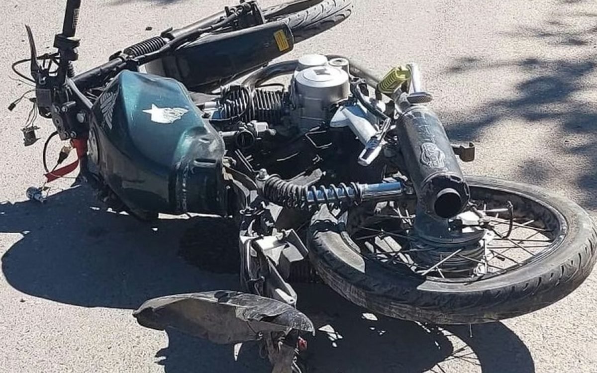 Motocicleta verde oscura caída sobre el asfalto después de un siniestro vial.