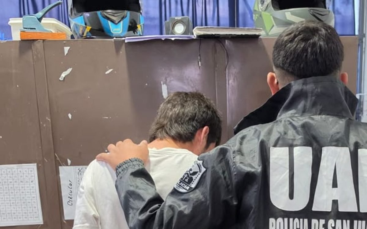 Un efectivo de la UAI de la Policía de San Juan, de espaldas, junto a un detenido en una oficina policial.
