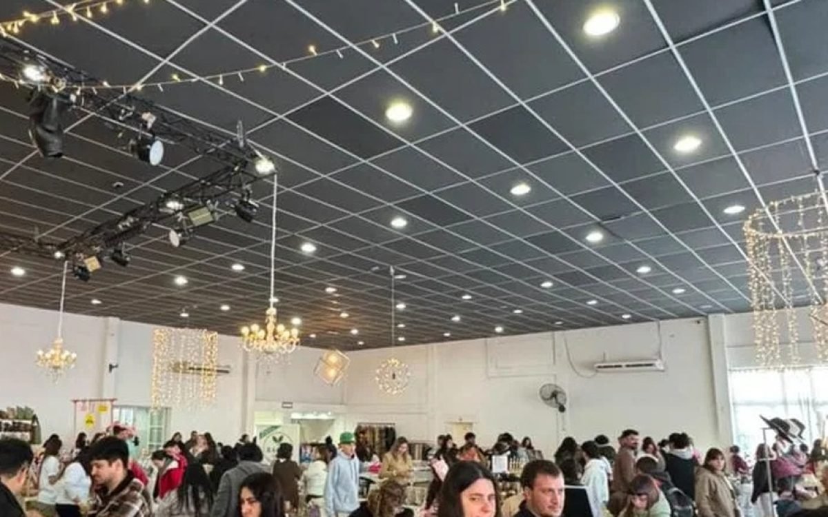 Salón con luces colgantes y público recorriendo puestos de emprendedores durante una feria.